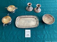 Full view of all six silver plated items on green tablecloth for overall lot presentation.