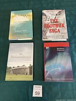 Four books including The Power of Now, The Beothuk Saga, The Rotinonhsonni, and Northern Exposure, arranged on green fabric with a lot tag number 59 visible.