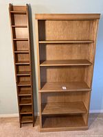 Wide shot showing both the narrow CD shelf and larger bookshelf standing side by side against a wall.