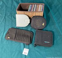 Photo of 5 CD cases and sleeves including a woven box, two black fabric cases, one white leather case, and one organizer style case.