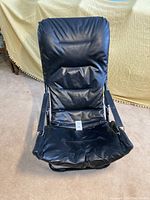 Front view of black folding chair with padded fake leather upholstery on metal frame.
