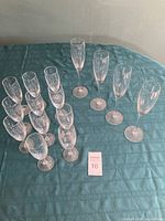 Photo showing both tall and short champagne flutes arranged on teal tablecloth.