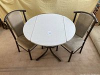Photo of round folding leaf kitchen table with two matching chairs placed on carpet.
