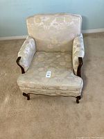 Front angle view of the living room chair showing floral upholstery on back, seat and arms with wood trim and carved legs.