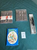 Four sets of lobster utensils and crackers arranged on dark green cloth; three sets in packaging and one set in original box