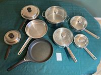 Photo showing full set of 8 pots and pans with lids including 4 Betty Crocker pots, 2 additional pots, stainless steel frying pan, non-stick frying pan, and steamer insert.