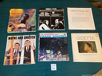 Six vinyl record covers on green cloth: Gola Sextet, Pablo Live with Joe Pass and Oscar Peterson, Gloria in Excelsis Deo, Wayne and Shuster comedy album, Frank Sinatra, and Odetta.