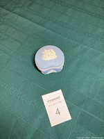 Small round Wedgewood blue candy dish with lid on green cloth.