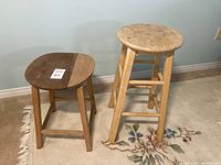 Two wooden stools side by side, showing one shorter dark wood stool and one taller lighter wood stool