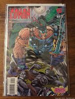 Front cover of Conan comic showing main character holding sword and crouching among wolves.