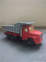 Side profile of red Majorette dump truck toy showing detailed cab and tipping bed