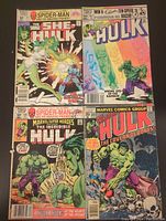 Four Marvel comic books displayed. One She-Hulk, three Hulk comics. Covers visible with characters and titles.