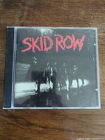 Front cover of Skid Row rock CD showing band members and red logo on black background