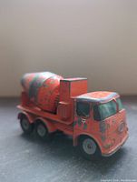 Front side view of the orange Matchbox concrete truck showing paint chipping and details of the cab and mixer drum