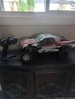 Photo showing the Traxxas Slash RC car on a surface along with the remote controller next to it, highlighting the car's exterior and branding.
