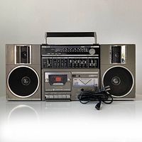 Front view of 1980's Eversonic boom box showing dual speakers, cassette player, control panel with sliders, LED peak meter, and tuning scale.