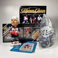 Wide view showing all items in the lot: Modano bobblehead, Hockey Greats coin album, Patrick Roy mini goalie mask in plastic, Vancouver Canucks team set, and OHL Memorial Cup set.
