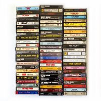 Photo of 73 assorted vintage music cassette tapes neatly arranged in rows showing visible album names and artists.