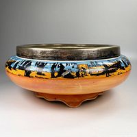 Side view of antique lustreware bowl showing fishing scene in black silhouette against blue and orange glaze and a silver hallmarked rim