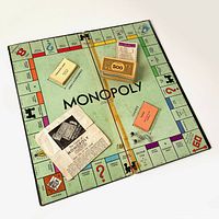 Folded Monopoly board with cards and money displayed in center, showing wear and tape at folds.