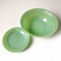 Top-down and angled view of both the jadeite serving bowl and saucer showing uniform pale green color and ribbed rim pattern.