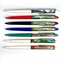 Top-down view of all seven vintage floaty pens showing colorful miniature scenes inside clear barrels and different colored caps/tips