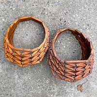 Pair of intricately constructed vintage wooden hanging plant baskets shown from above on a concrete surface.