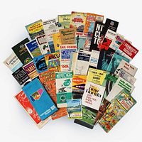 Shows a wide spread of various vintage maps and travel brochures laid out in a fan shape, covering multiple regions including Florida, New York, Massachusetts, Nassau, Quebec, and others. Visual condition appears consistent with vintage paper items, some wear and discoloration.