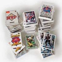 Several stacks of sports cards layered and fanned out showing various hockey and baseball sets including MVP Checklist, All Stars Joueurs Etoiles, NHL All Star Fantasy Suite De Reve, and individual cards in protective sleeves.