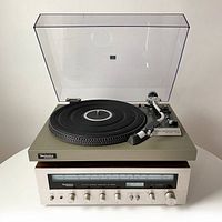 Front view of Technics SL-23 turntable placed on top of Technics SA-5060 stereo receiver with clear dust cover open.