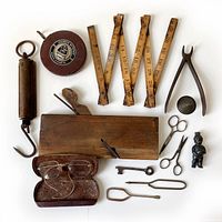 Photo showing full lot with all 13 vintage tools including measuring tapes, wooden ruler, smoothing plane, pliers, scissors, eyeglasses in case, key and small metal items.