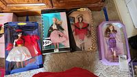 Four Barbie dolls in original packaging placed on floor, showing overall lot