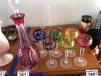 Decanter and six stemmed glasses displayed on a wooden surface with intricate cut and etched patterns.