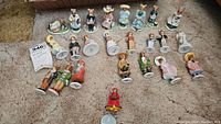Overview photo of 21 ceramic bunny figurines arranged on carpet, showing variety of styles and costumes.