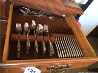 Wooden box open showing five felt-lined slots with forks, spoons, knives and serving utensils on top