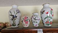 Four vases displayed side by side showing the floral and bird designs on porcelain.