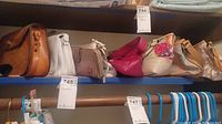 Shelf showing 7 ladies purses and wallets of various colors and styles.