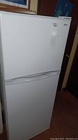 White Haier refrigerator front view showing full unit with freezer on top and fridge below.