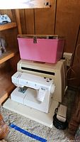 Kenmore sewing machine in carrying case beneath a pink sewing box
