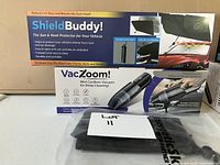 Photo showing ShieldBuddy sun and heat protector box with key features and VacZoom mini cordless vacuum box with accessories and carry case.