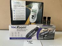 Photo showing CarMD Vehicle Health System box, two small bottles of automotive fluid, and VacZoom mini cordless vacuum box.