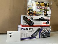 Lot includes Bell+Howell night vision glasses, Accel Air portable tire inflator, VacZoom mini cordless vacuum in retail boxes.