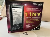 Photo of the Aluratek Libre eBook Reader PRO packaging, showing device image and key features like Exclusive LCD technology, 2GB SD card, and 100 ebooks included.