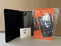 Tablet package is sealed in original orange box with 16GB storage marked. Black protective cover is opened and shown beside it with signs of wear and damage on interior surface.