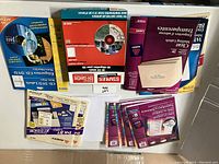 Photo showing multiple packages of labels for inkjet and laser printers, including purple and red boxes with various label types.