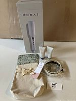 Photo of boxed Monat hair volumizer device with two small hand creams and fabric gift bag tagged with bow.