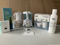 All items laid out on table showing dental calculus remover, oral irrigator, teeth whitening set, and mouthwash.