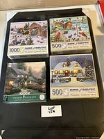 View of the puzzle board and all four boxed puzzles, showing box art with winter and holiday scenes and piece counts.