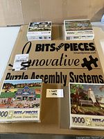 Photo of large Bits and Pieces puzzle assembly board and four brand new 1000-piece puzzles with distinct scene images.