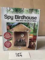 Front of box showing the Spy Bird House with emphasis on suction cups that attach to glass surfaces and clear plexiglass visualization panel.